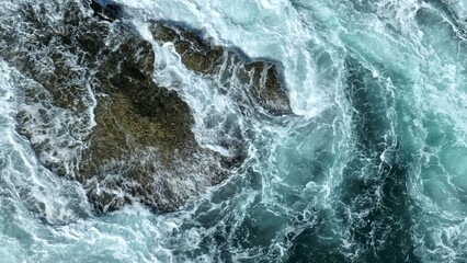 The swirling sea spray and crashing waves against the rocky coastline reflect the intensity of the...