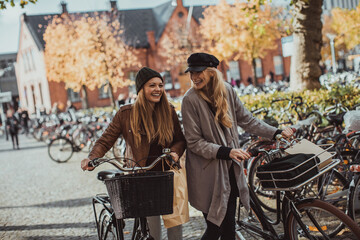 Obraz premium Young women pushing their bicycles on a city street