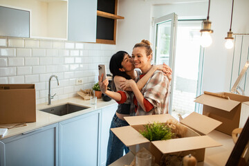 Happy lesbian couple embracing in new home while moving in