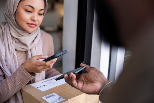 Woman in hijab making mobile payment with QR code