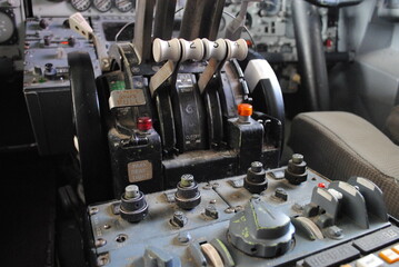 Cockpit levers and controls of a vintage aircraft, showing throttle and parking brake