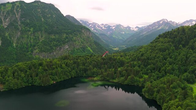 Drone views of Freibergsee and Heini-Klopfer- Schkiflugschanze in Bavaria, Germany. Surrounded by mountains and forests, this pristine lake and famous ski jump is an aerial view of area. Oberstdorf. 