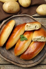 Tasty baked patties with potato and parsley on wooden table, flat lay