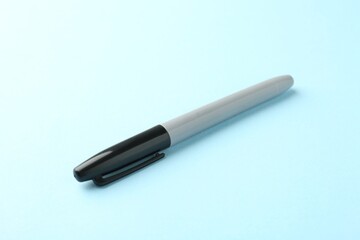 One black marker on light blue background, closeup. Space for text