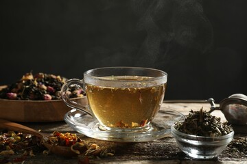 Refreshing herbal tea and dry leaves on wooden table, closeup. Space for text