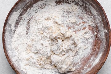 Overhead view of paratha dough being mixed in a wooden bowl, top view of flaky flatbread dough in a wood bowl, process of making paratha