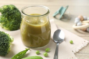 Baby food. Tasty puree in glass jar, ingredients and spoon on table, closeup