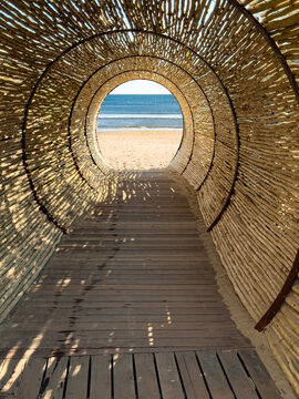 Wooden tunnel to the sandy beach under a bright blue sky