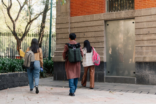 Three unrecognizable students walking around the university campus.