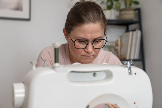 Focused woman using sewing machine

