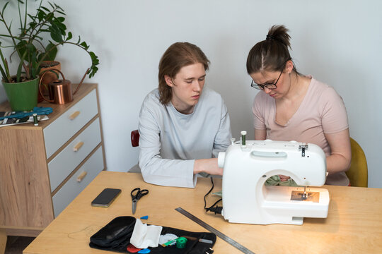 Two people sewing fabric together using sewing machine
