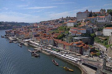 Obraz premium A cityscape view of the Ribeira historical district of Porto, Portugal is shown alongside the Douro River during the day.