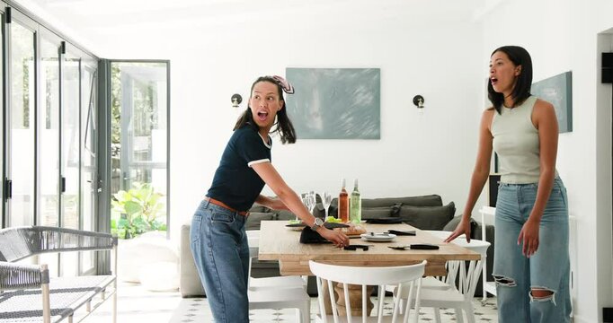Diverse female friends at dining table greeting guest with hug, opening box for sharing headbands
