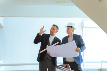 Architect and engineer reviewing blueprints at construction site