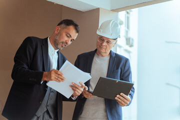 Architect and engineer reviewing blueprints at construction site