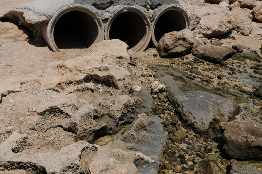 Concrete pipes and rocky shoreline near water at a coastal area