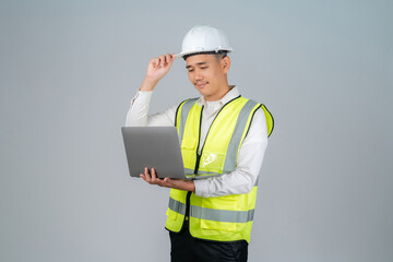 Smiling young Asian engineer or worker working with laptop in studio on grey background.