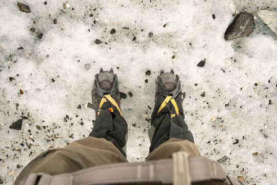 POV shot of hiking boots and crampons on icy terrain