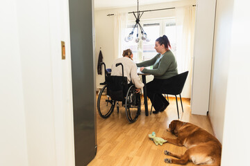 Caregiver Assisting Woman in Wheelchair at Table