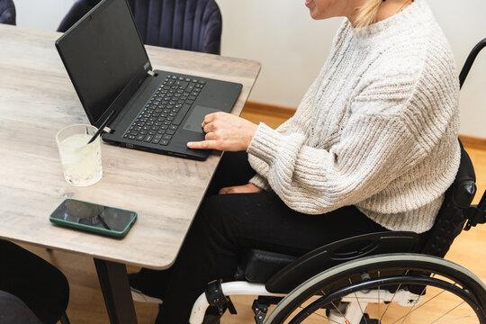 Woman in Wheelchair Working on Laptop in Kitchen