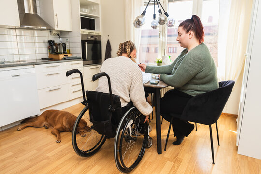 Caregiver Assisting Woman in Wheelchair at Table