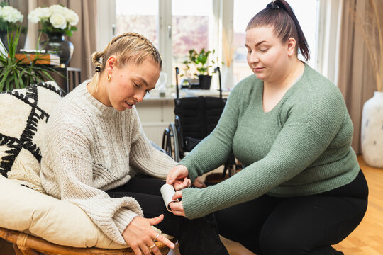 Caregiver Using Lint Roller on Young Woman's Clothing