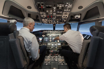 Airplane pilots operating aircraft flight deck controls during flight