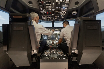 Airline pilots operating aircraft flight simulator cockpit controls