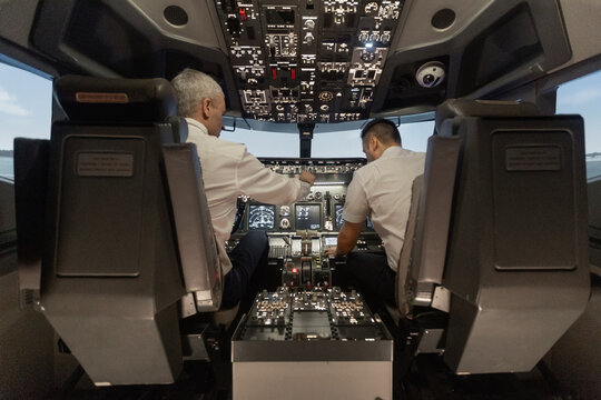 Airline pilots operating aircraft flight simulator cockpit controls