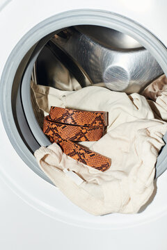 Washing a patterned belt and a pair of beige garments in a machine