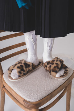 Stylish individual showcasing leopard print slippers on a chair
