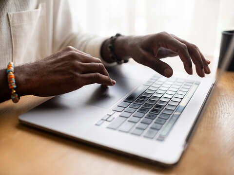 Person Typing on a Laptop at a Wooden Desk in Natural Light