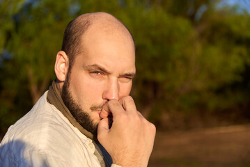 Hispanic male traveler sitting on the bank of a stream at dawn, receiving the first rays of sunshine as he enjoys eating a cookie. El Palmar National Park, Entre Rios, Argentina.