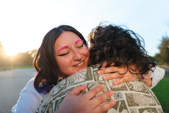 Latin non-binary couple embracing at sunset in a park