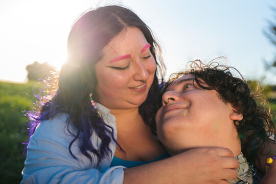 Non-binary people hugging in a park during a sunny day