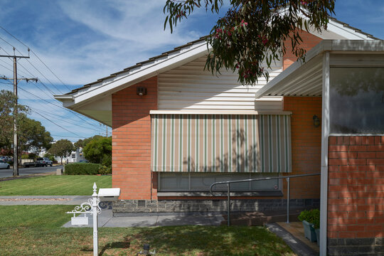 Sunny home with striped awning in suburban area