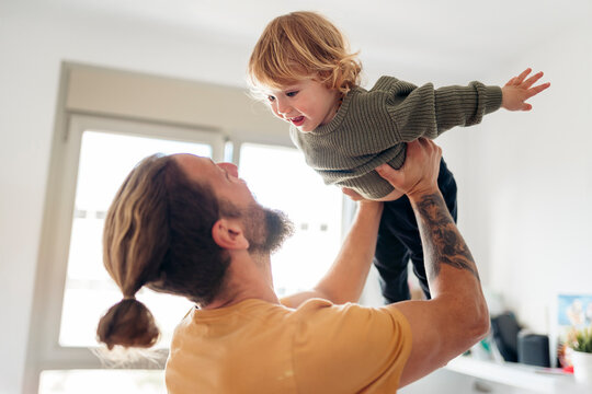 Father lifting his toddler son, playing together at home