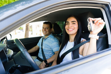 Happy couple showing new car keys while driving