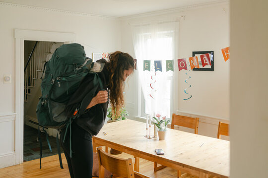young woman with backpack coming home 