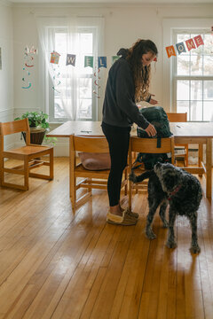 dog welcoming young woman with backpack coming home, 