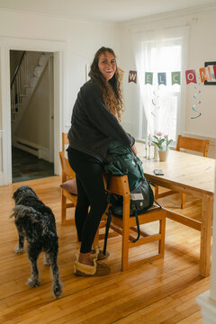 dog welcoming young woman with backpack coming home, 