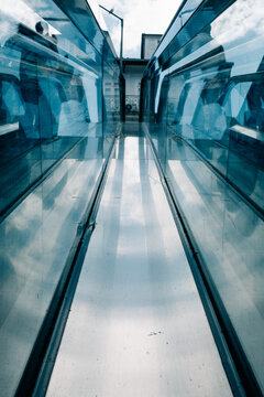 Reflections in mirrored glass of escalator tunnel