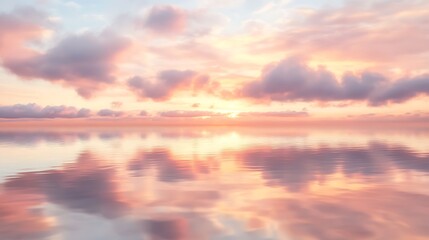 Obraz premium Calm Water Reflecting Soft Sunset Sky with Clouds