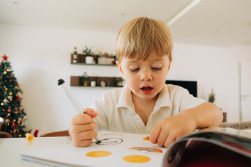 Focused child coloring and using stickers in activity book