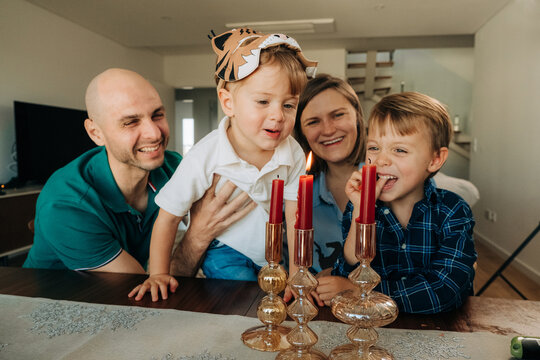 Naklejki Curious child reaches for candle as family laughs together