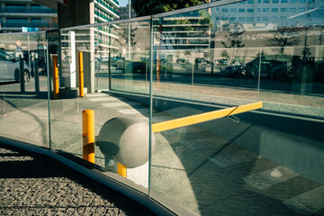 Modern glass barrier and yellow security bar in city
