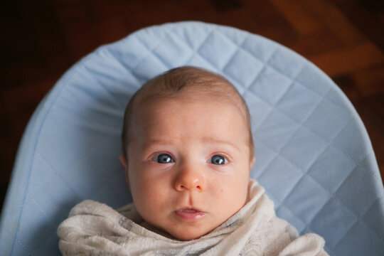 Baby with blue eyes in a baby bouncer