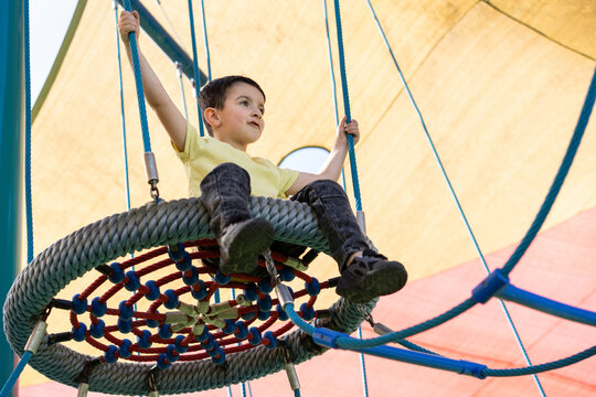 Child Enjoys Swinging on a Large Circular Rope Swing Outdoors