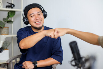 Podcast Host Greets Guest with Fist Bump While Filming Conversation in Studio.