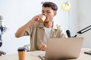 Asian Blogger Man Drinking Coffee During Live Podcast in Recording Studio